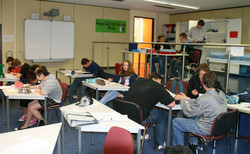 Klassenraum mit SchülerInnen, Whiteboard im Hintergrund.